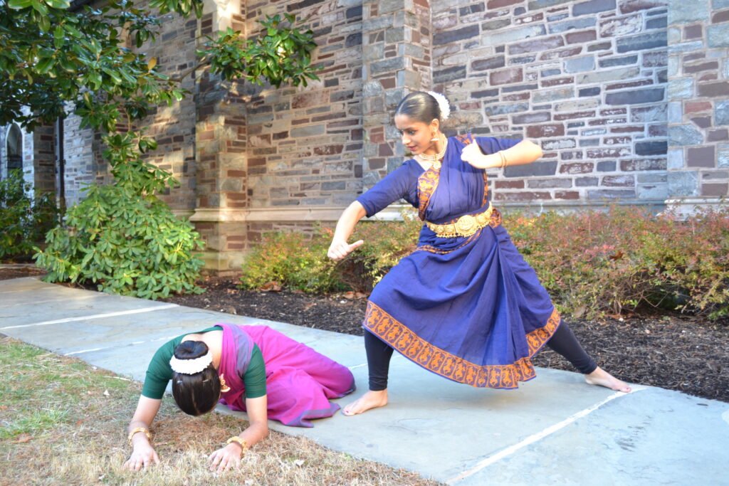 two dancers in a pose where a warrior stabs a demon on the floor